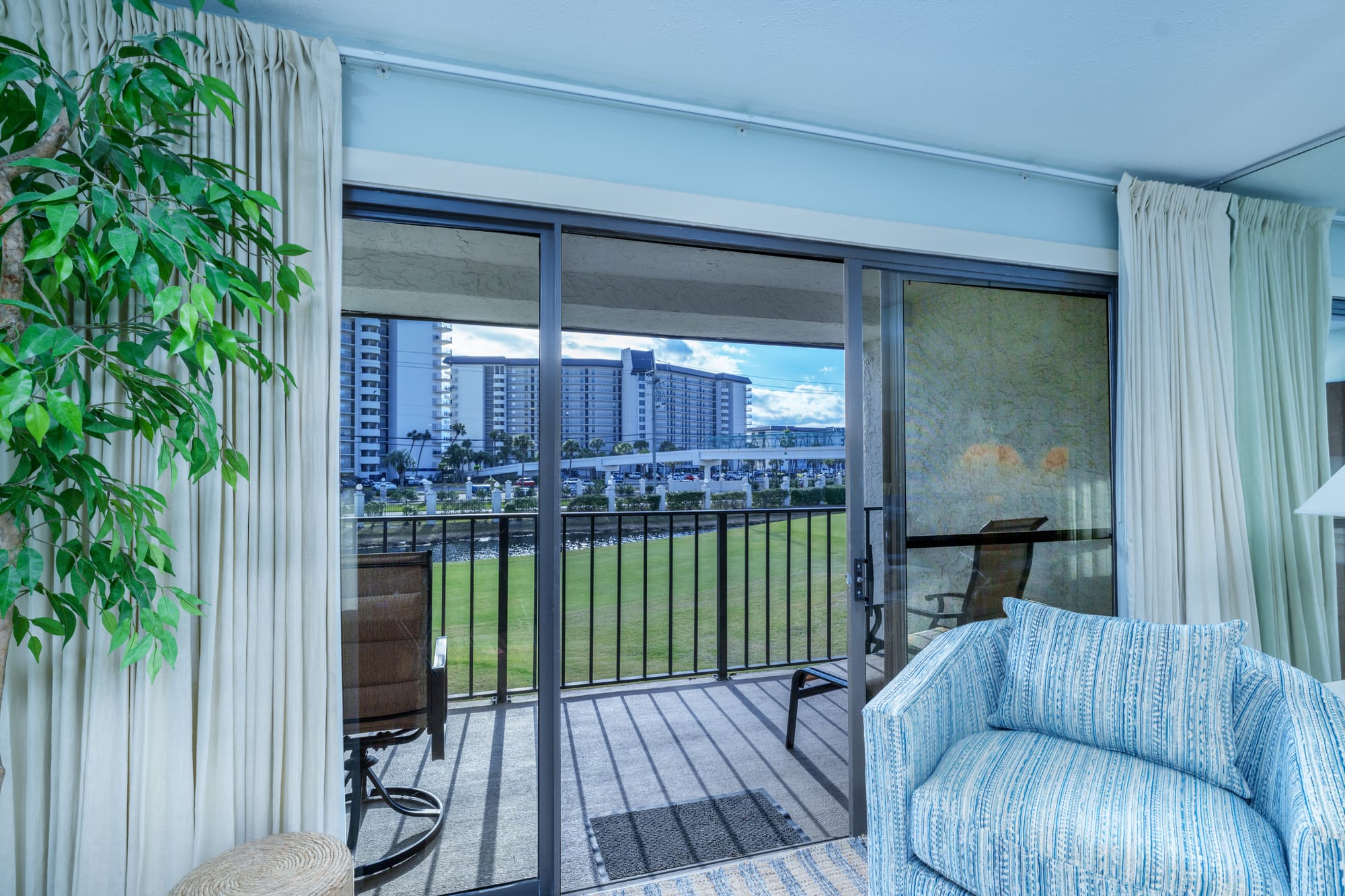 Sliding glass door from the living room onto a balcony with two chairs.