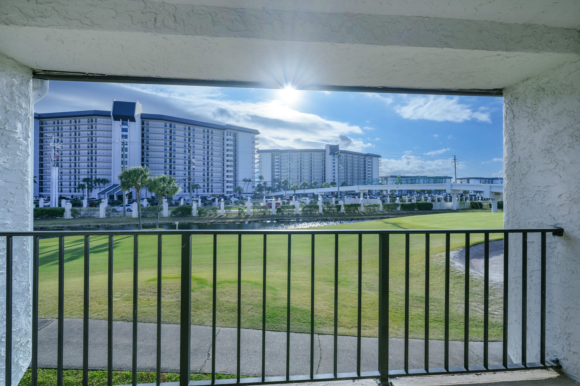 View from the balcony across a green lawn toward nearby high-rise buildings.