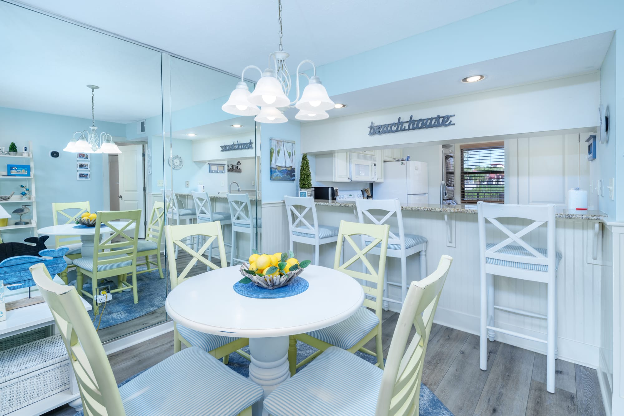 Round white dining table with four chairs, and three stools at the kitchen counter.