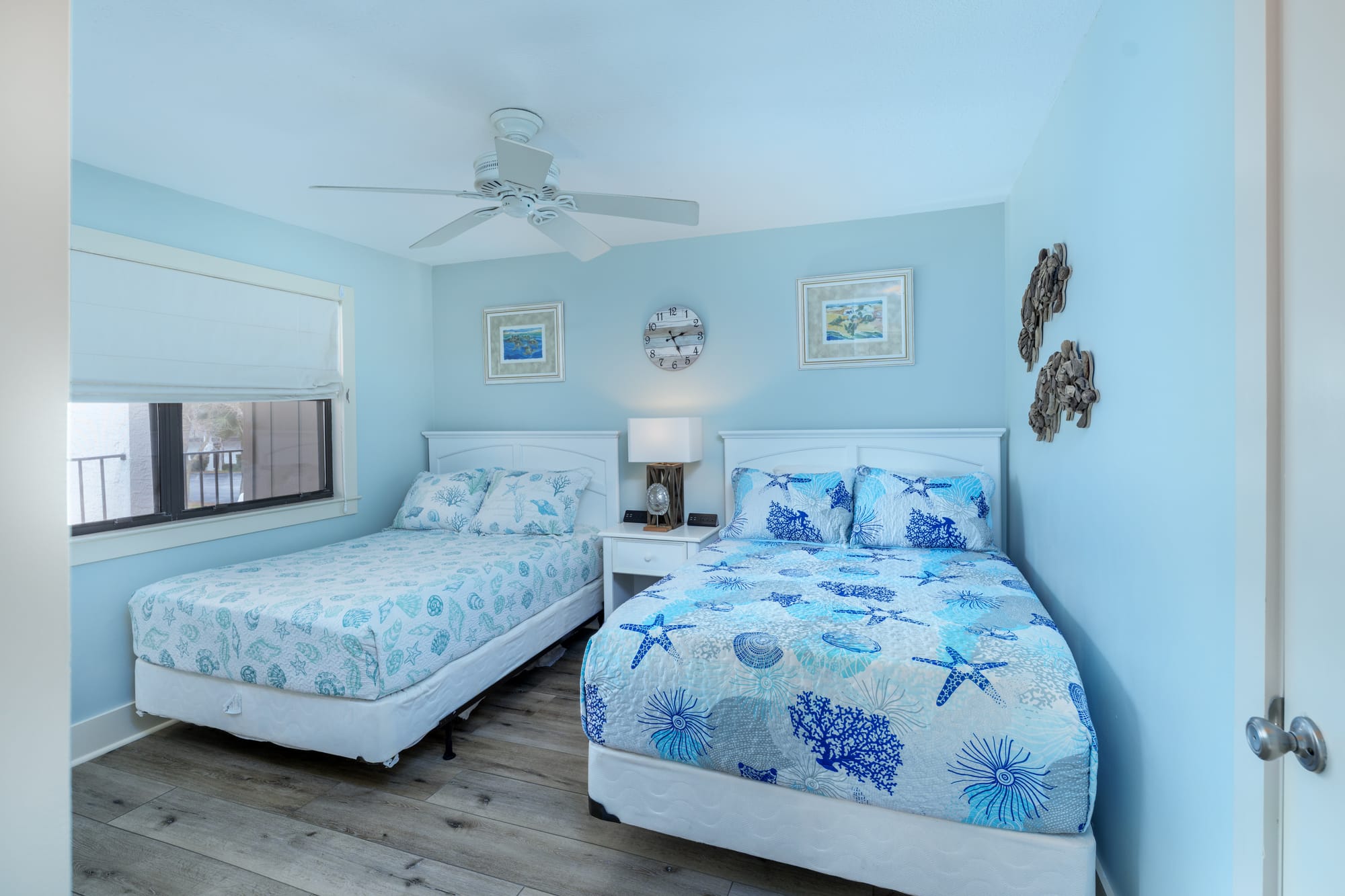 Second bedroom with two full beds, a shared nightstand, a ceiling fan, and a window.
