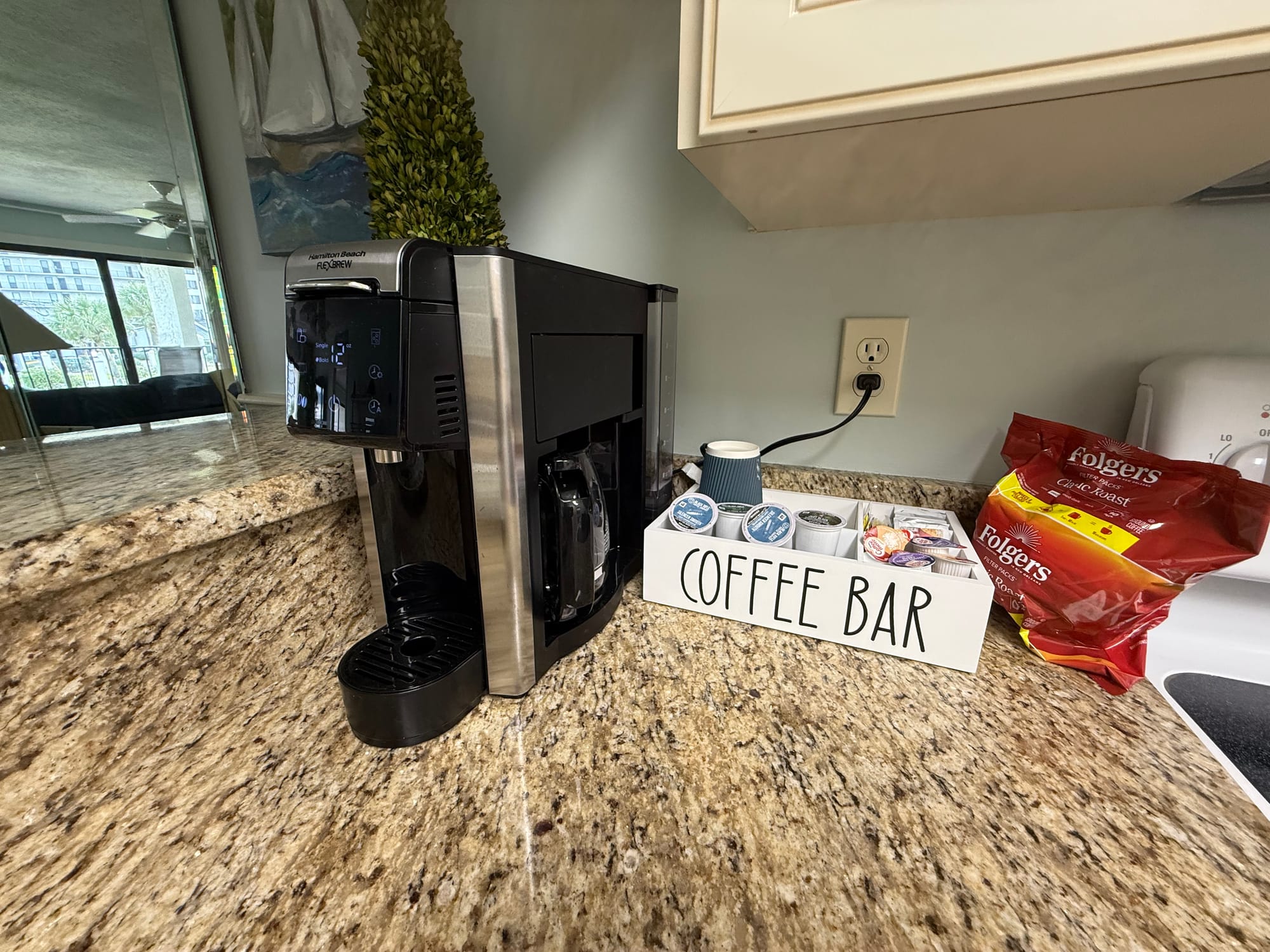 Kitchen coffee bar with a pod and carafe brewer, a box of pods, and a bag of ground coffee.