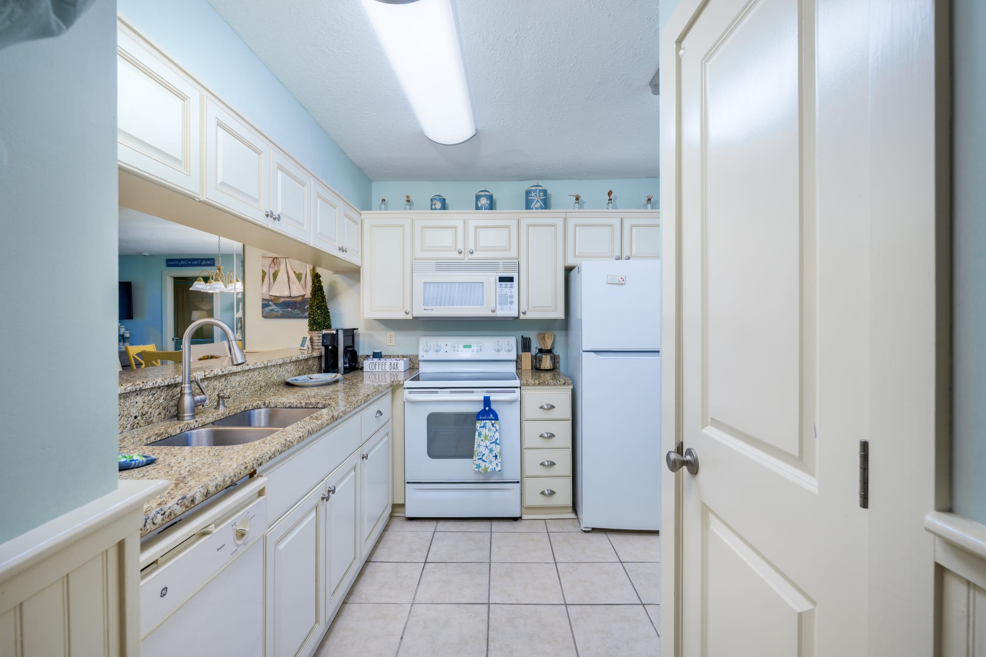 Kitchen seen from the doorway, with the sink along the left wall and the range and refrigerator at the far end.