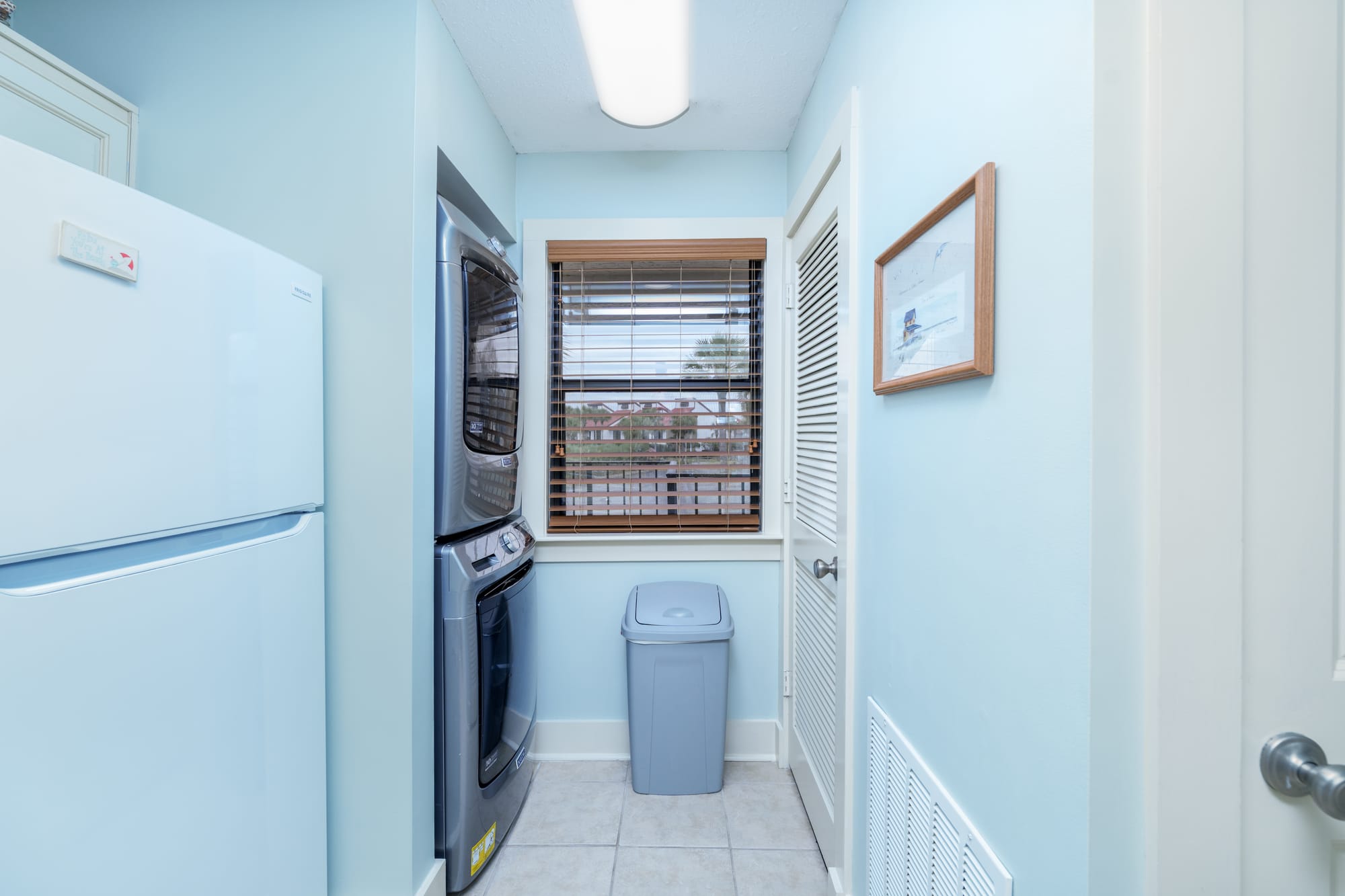 Stacked washer and dryer in a closet next to the refrigerator.