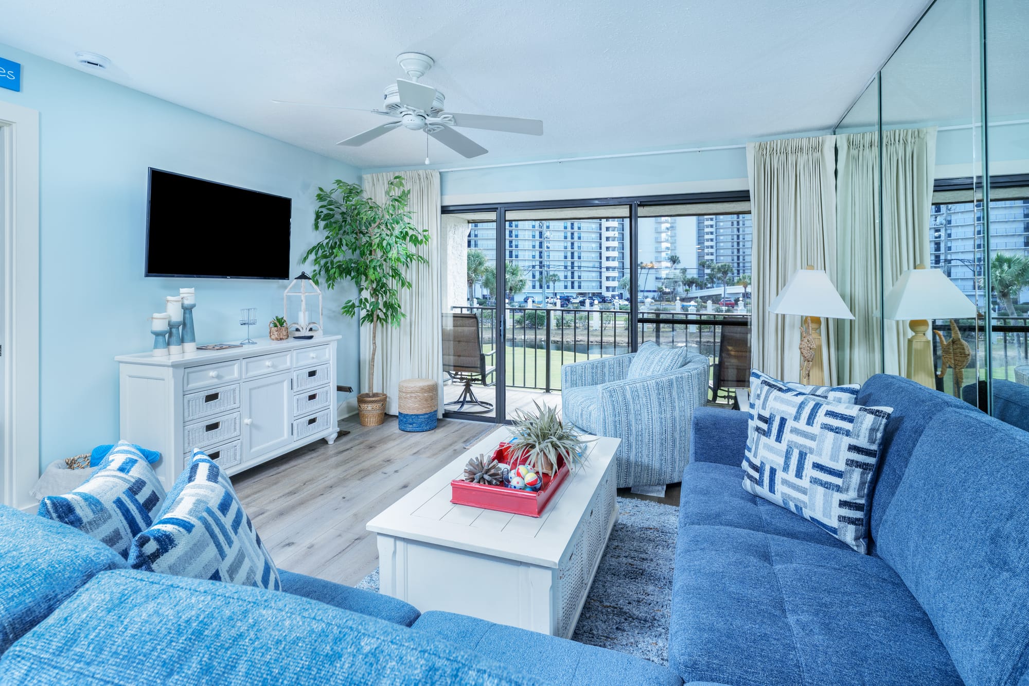 Blue sectional and white coffee table facing an armchair and the balcony.