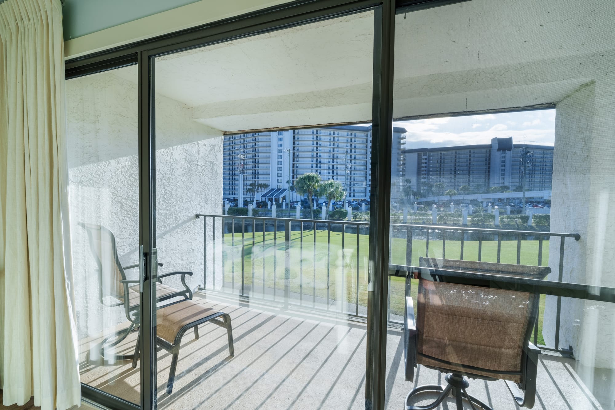 Sliding glass door from the primary bedroom onto a balcony with two chairs.